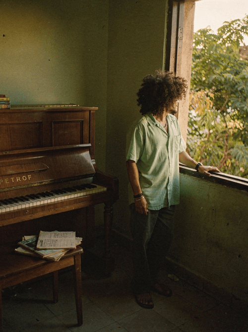Gabriel beside a Petrof piano at dusk