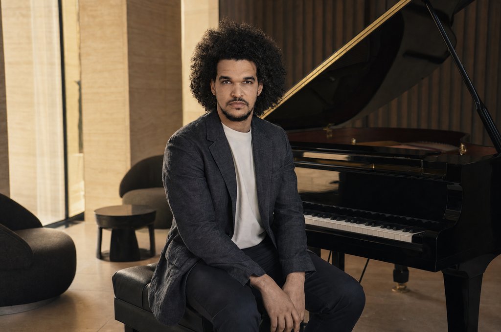 Gabriel Oramas seated beside a grand piano
