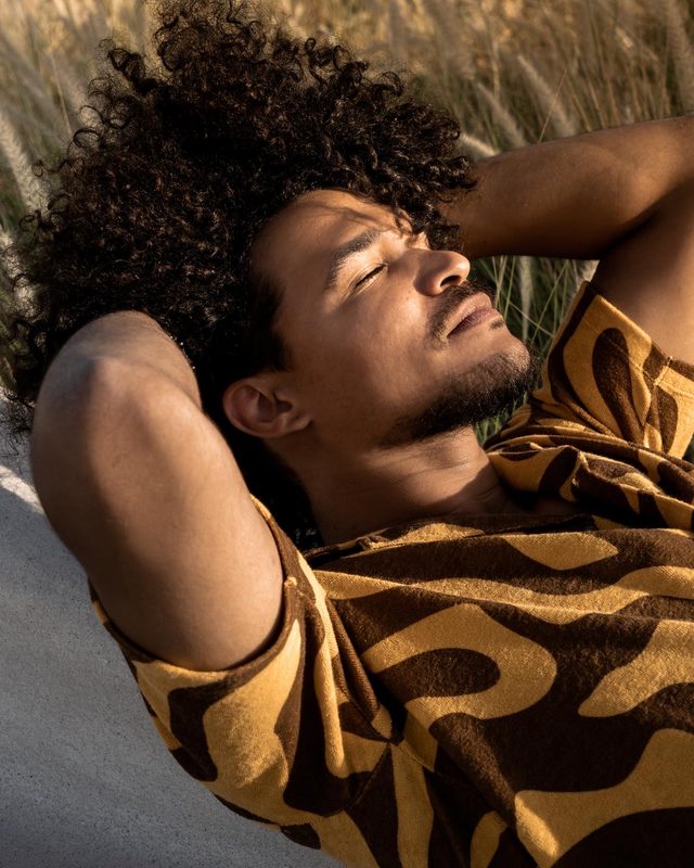 Gabriel Oramas lying back in golden light with both arms behind his head, eyes closed, face in profile